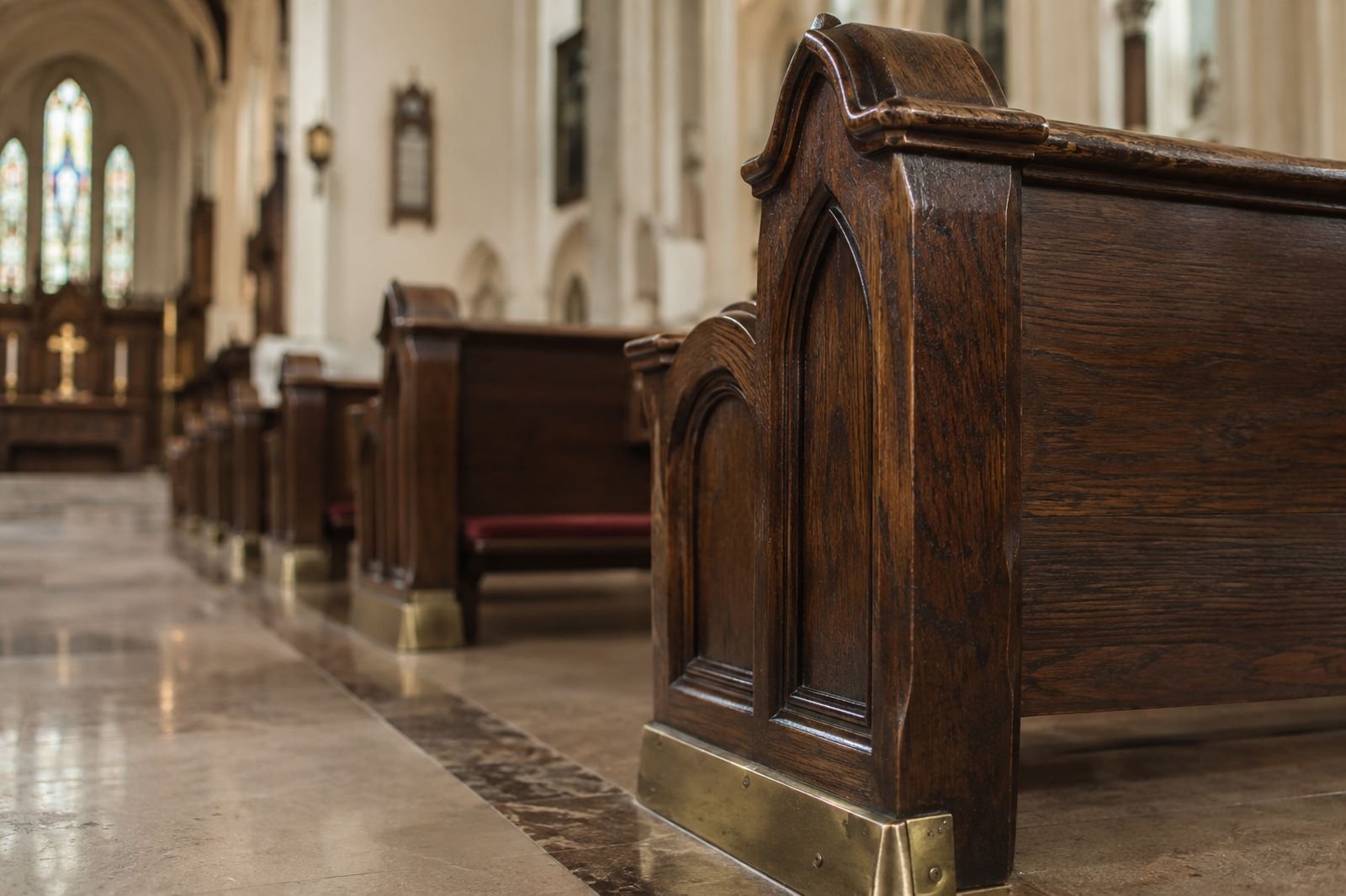 Carved solid oak pew end with a brass floor bracket